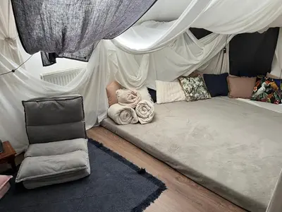 a bed in a room with curtains and a chair at Spacious flat & parking possibility, 3 stops to Wenceslav square in Prague