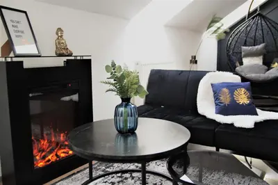 a living room with a black couch and a fire place at Spacious flat & parking possibility, 3 stops to Wenceslav square in Prague