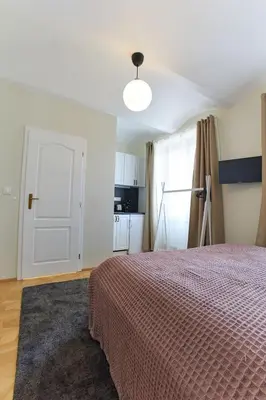 a bedroom with a bed and a white door and a kitchen at River View Residence by Charles Bridge in Prague