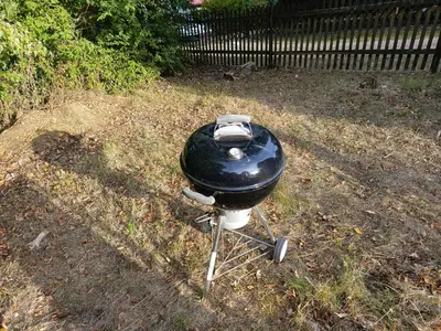 a charcoal grill sitting in the grass next to a fence at Slapy chata Županovice in Županovice