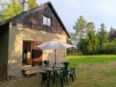a table with an umbrella in front of a barn at Slapy chata Županovice in Županovice