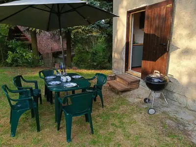 a table and chairs with an umbrella and a grill at Slapy chata Županovice in Županovice