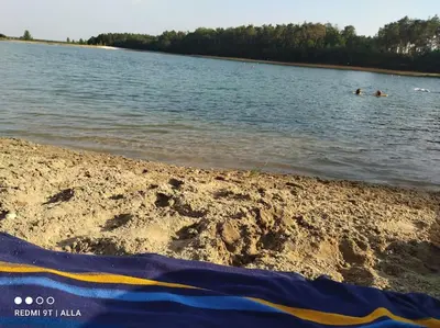 a beach with two people swimming in the water at Okouzlující vila u jezera Lhota in Lhota