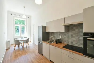 a kitchen with white cabinets and a table with chairs at WSP Petrin Garden Apartments in Prague