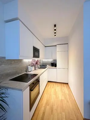 a kitchen with white cabinets and a wooden floor at Apartment with Free Parking in Prague in Prague