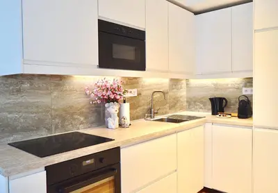 a kitchen with white cabinets and black appliances at Apartment with Free Parking in Prague in Prague