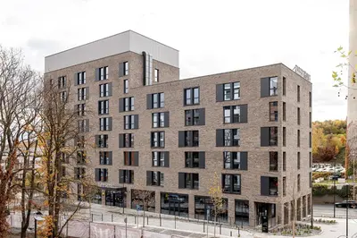 a large brick building with black windows at Zleep Hotel Prague in Prague