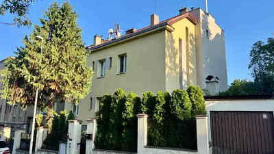 a white house with a fence and a tree at Apartmán III Praha - centrum in Prague