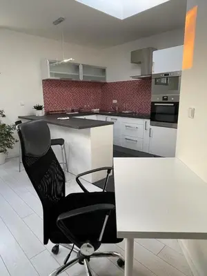 a kitchen with a black chair and a white table at RUMAKO apartments in Prague