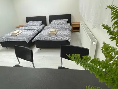 two beds in a room with two chairs at RUMAKO apartments in Prague