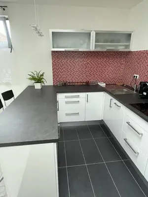 a kitchen with white cabinets and a black counter top at RUMAKO apartments in Prague