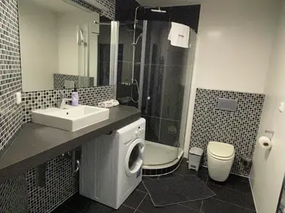 a bathroom with a sink and a washing machine at RUMAKO apartments in Prague