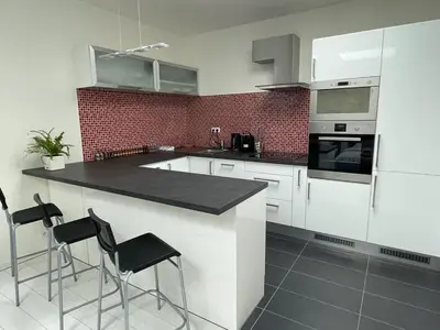 a kitchen with white cabinets and black counter stools at RUMAKO apartments in Prague