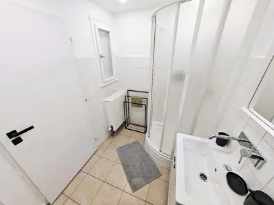 a white bathroom with a shower and a sink at Zizkov studio -004- in Prague