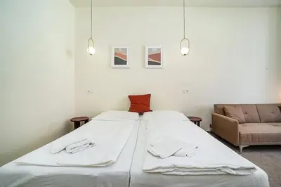 a bedroom with a bed with white sheets and a couch at Modern, bright studio in a great location in Prague