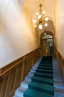 a hallway with blue stairs in a building with a chandelier at Prague Castle King's Chic in Prague