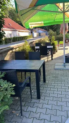a picnic table with chairs and a green umbrella at Chatka Jägerhaus K myslivně 26 in Libochovice