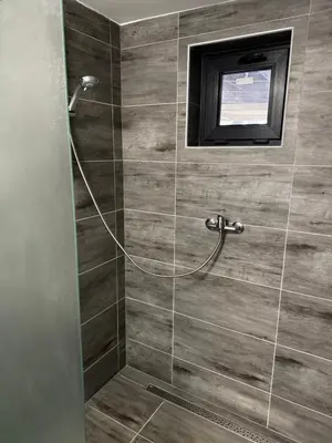 a bathroom with a shower with a television on the wall at Chatka Jägerhaus K myslivně 26 in Libochovice