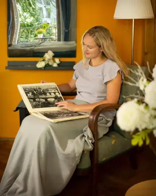 a woman sitting in a chair with a laptop at Triple King Size Balcony Suite in Prague