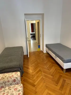 two beds in a room with a wooden floor at 2B Pechackova family apartment with balcony by the river in Prague