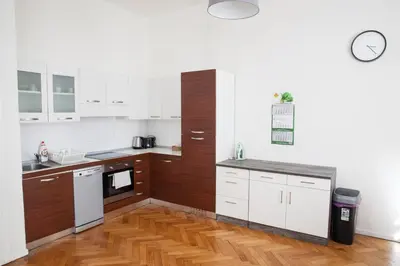 a kitchen with white cabinets and a wooden floor at 2B Pechackova family apartment with balcony by the river in Prague