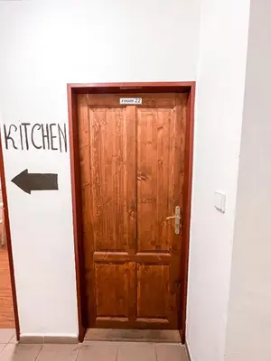 a wooden door in a white room with a sign at 3 Apartments in 1 location in Prague
