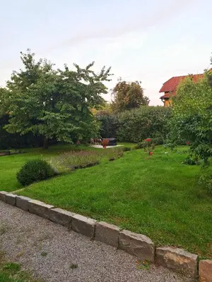 a yard with green grass and a stone wall at Apartmán Nad hradem in Týnec nad Sázavou