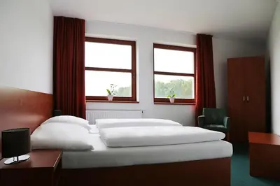 a bedroom with a large bed with two windows at Sporthotel Hostivice in Hostivice