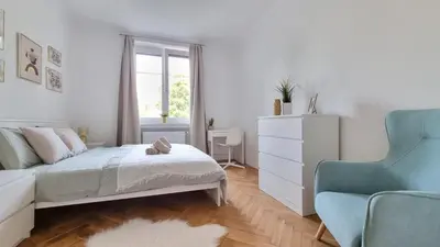a white bedroom with a bed and a chair at Finnem Rentals Průběžná in Prague