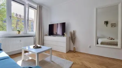 a white living room with a tv and a table at Finnem Rentals Průběžná in Prague