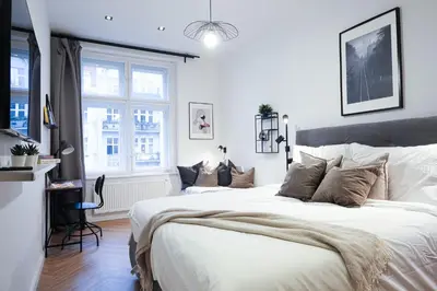 a white bedroom with a large bed and a window at Rentero Cozy Apartment in picturesque Prague district in Prague