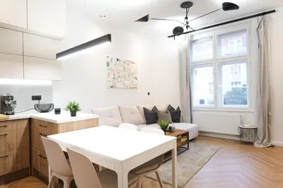 a kitchen and a living room with a white table at Rentero Cozy Apartment in picturesque Prague district in Prague