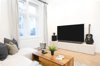 a living room with a white couch and a tv at Rentero Cozy Apartment in picturesque Prague district in Prague