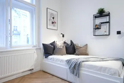 a bed in a white room with a window at Rentero Cozy Apartment in picturesque Prague district in Prague