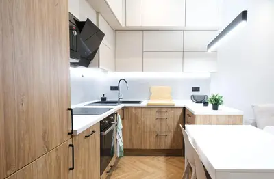 a kitchen with white counters and wooden cabinets at Rentero Cozy Apartment in picturesque Prague district in Prague