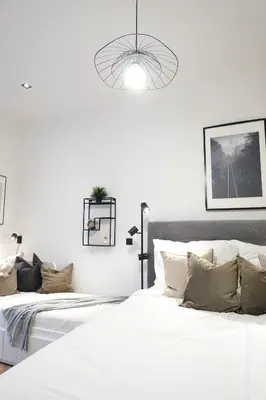 a white bedroom with two beds and a pendant light at Rentero Cozy Apartment in picturesque Prague district in Prague