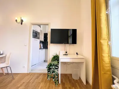 a living room with a table and a tv on a wall at Beautiful & peaceful apartment with cute balcony in Prague