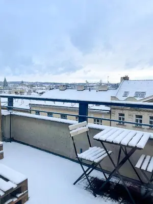 a snow covered balcony with a chair on a roof at Vantisch Studio in Prague