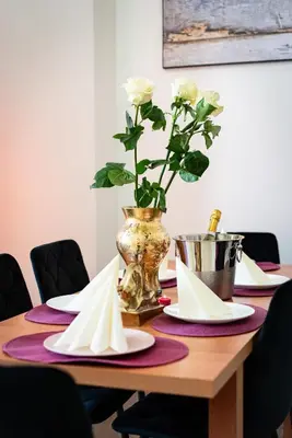 a wooden table with plates and a vase with flowers at Emperors Elegance Suite in Prague