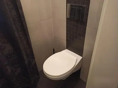 a bathroom with a white toilet in a tiled wall at Emperors Elegance Suite in Prague