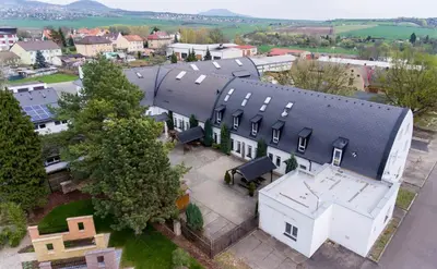 an aerial view of a large white house with a black roof at Hotel Koliba in Litoměřice