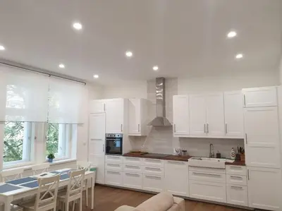 a kitchen with white cabinets and a table and chairs at Prague Downtown Vinohrady - next to Havlícek Park in Prague