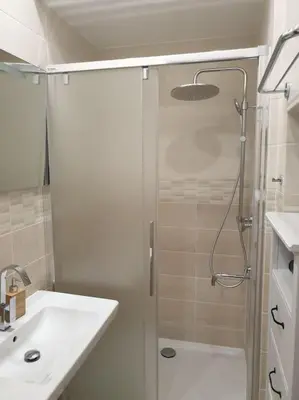 a white bathroom with a shower and a sink at Prague Downtown Vinohrady - next to Havlícek Park in Prague