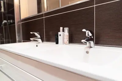 a bathroom sink with two faucets and a mirror at Prague Marina River View Apartment Close To City Centre FREE PARKING in Prague