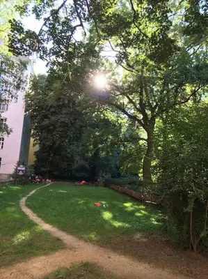 a green yard with a tree and a path at Byt v srdci Žižkova Praha 3 in Prague