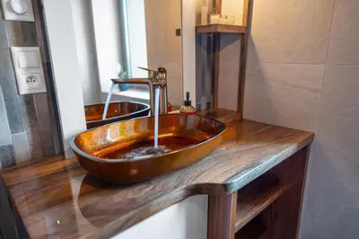 a bathroom with a copper bowl sink on a wooden counter at LASKARA Garden Apartment by Prague Forest in Nové Jirny