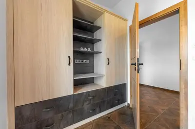 a walk in closet with wooden cabinets and a door at LASKARA Garden Apartment by Prague Forest in Nové Jirny
