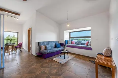 a living room with a purple couch and a window at LASKARA Garden Apartment by Prague Forest in Nové Jirny