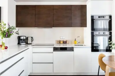 a white kitchen with wooden cabinets and appliances at TurnKey I Central Apartment with Terrace in Prague