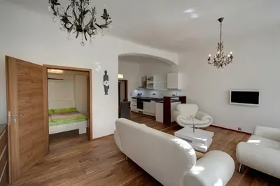 a living room with white furniture and a kitchen at Historic Centre Apartments II in Prague